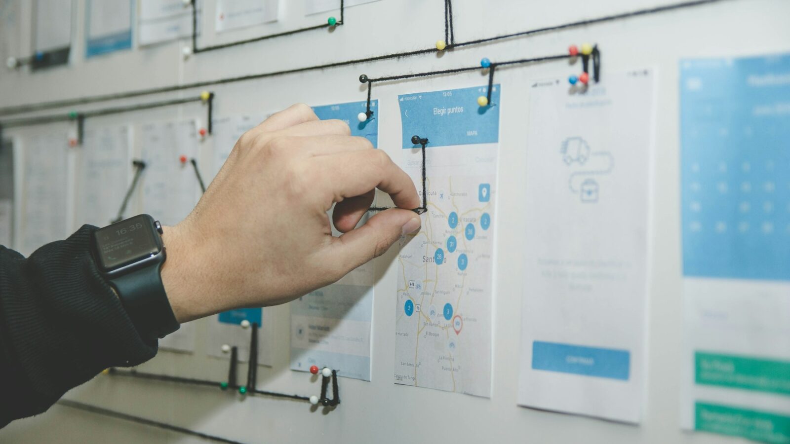 A person arranging process cards and notes on a planning wall